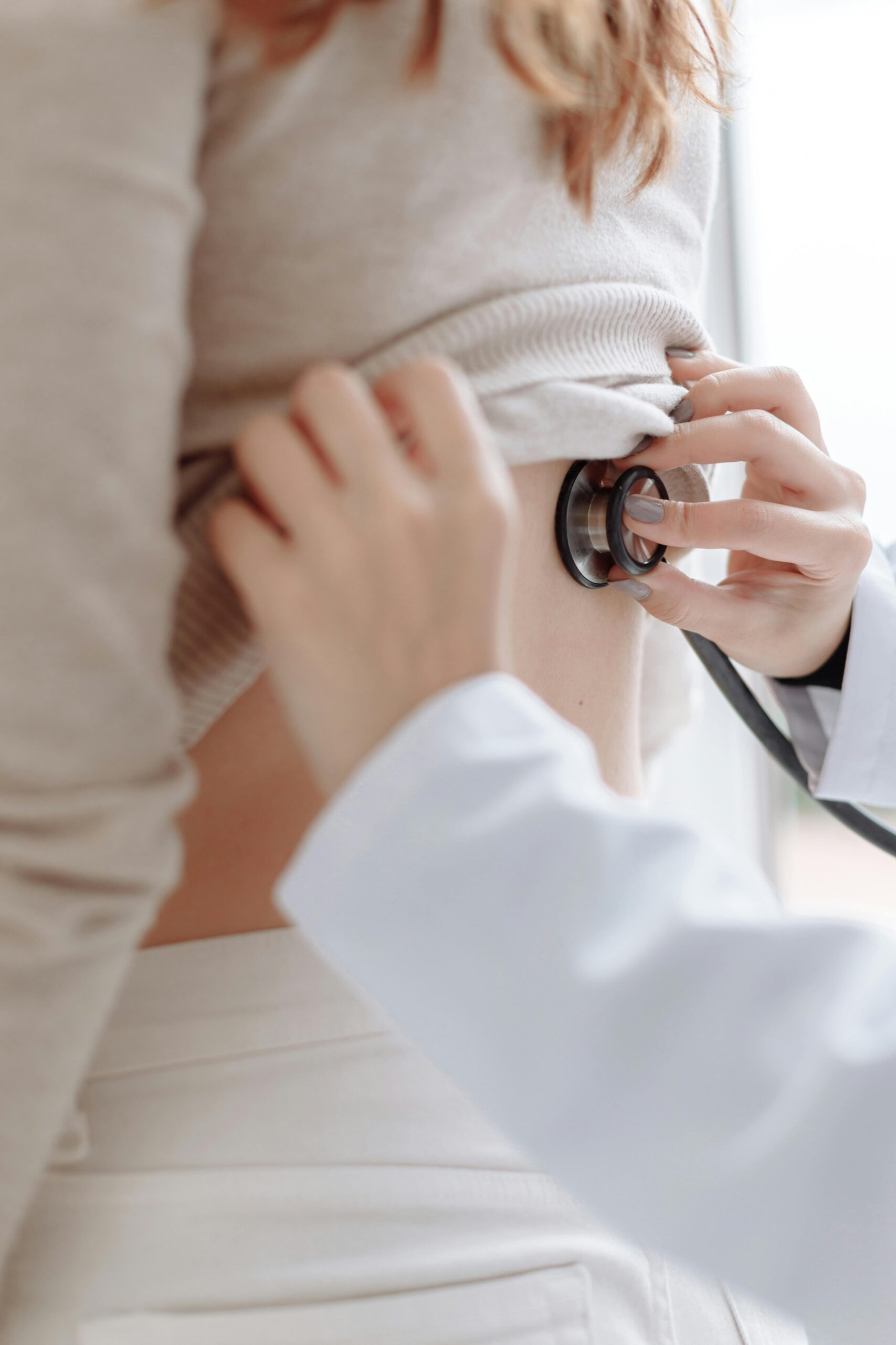A close up of a doctor placing a stethoscope onto a ladies back. A close up of a doctor placing a stethoscope onto a ladies back.