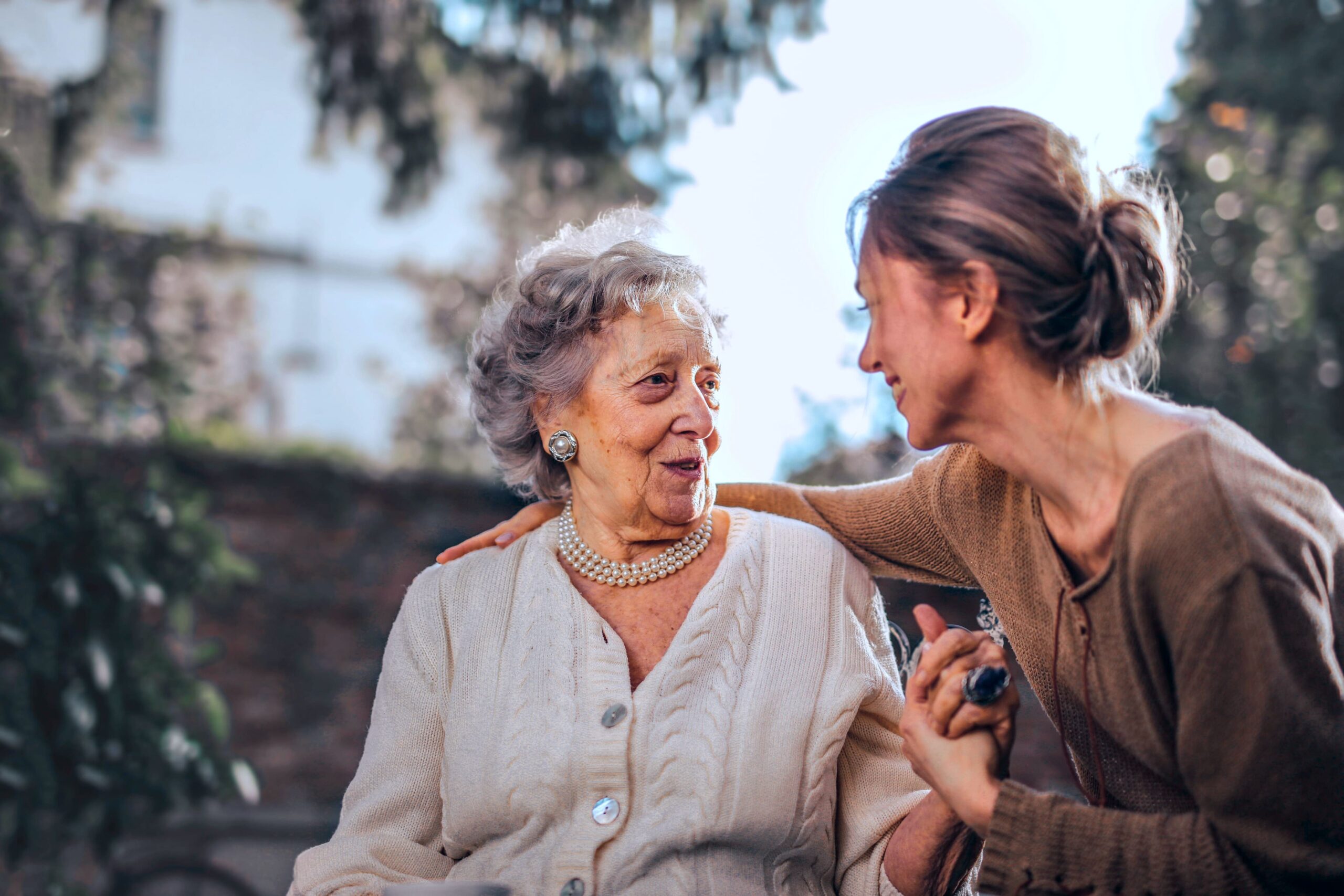 A younger woman embraces an elderly woman while in conversation together. A younger woman embraces an elderly woman while in conversation together.